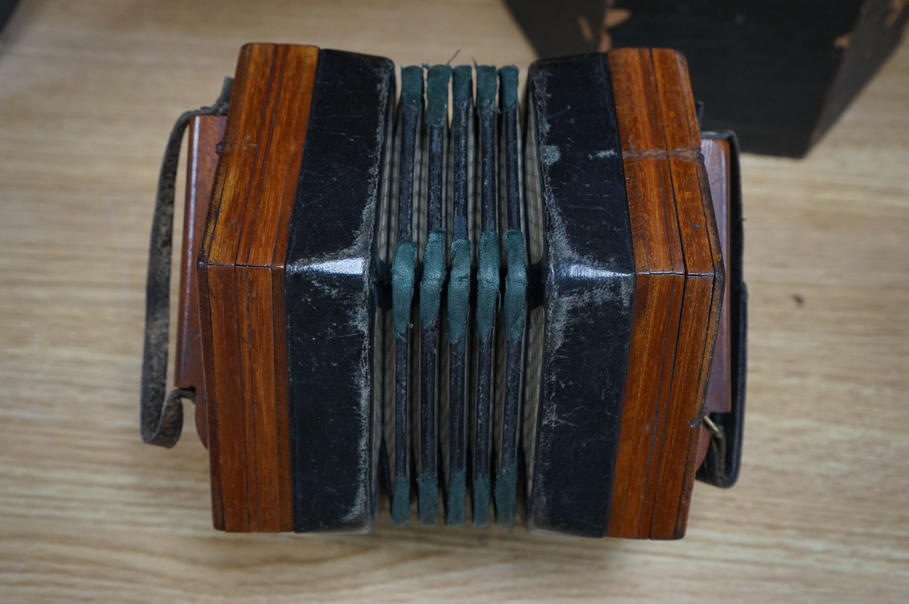 A cased accordion with paper label for C. Jones, bone buttons, 17cm wide. Condition - box worn, accordion strap torn and leather rubbed to edges of accordion